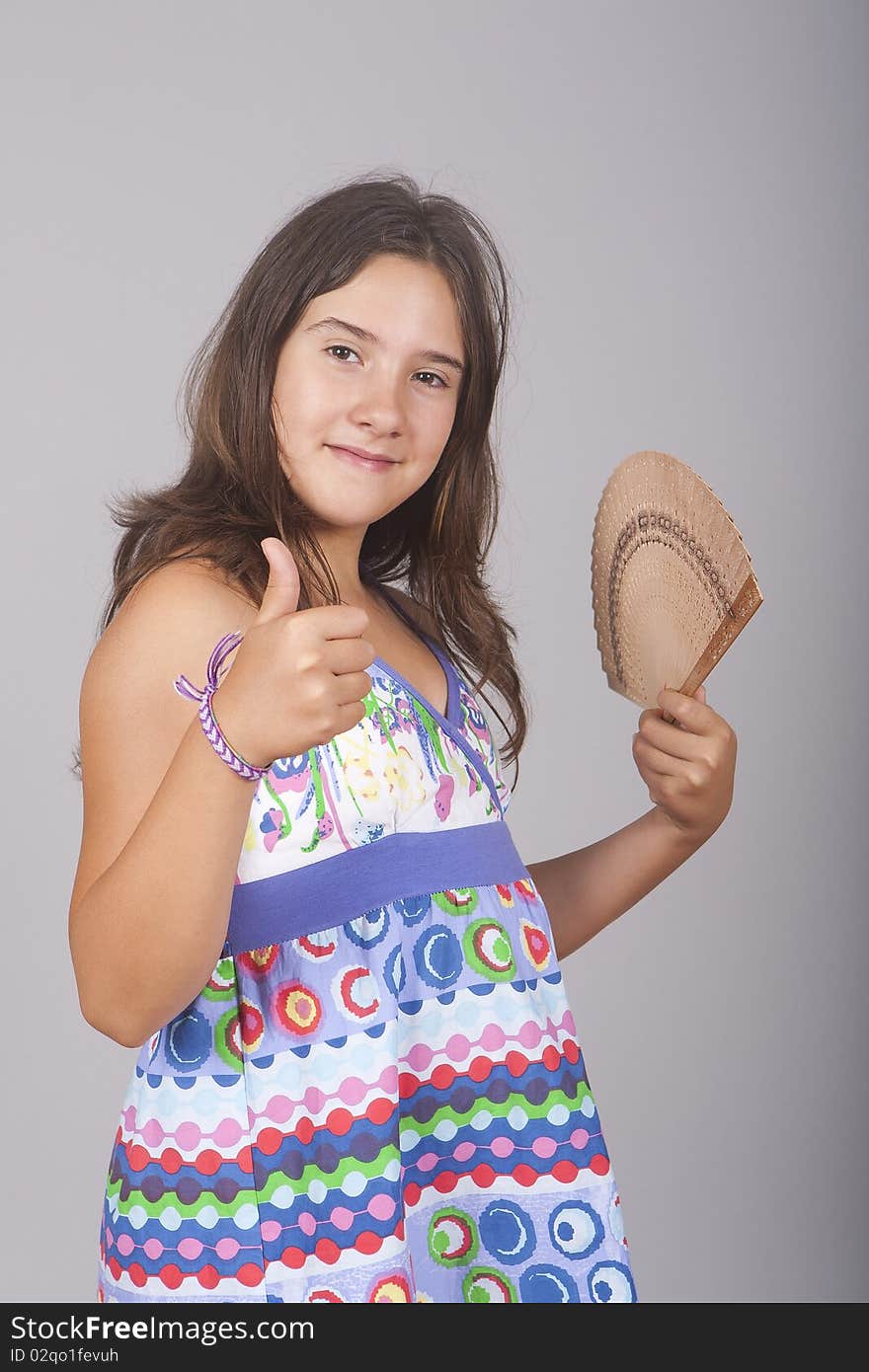 Young girl with a fan in one hand and positive sign with the other. Young girl with a fan in one hand and positive sign with the other