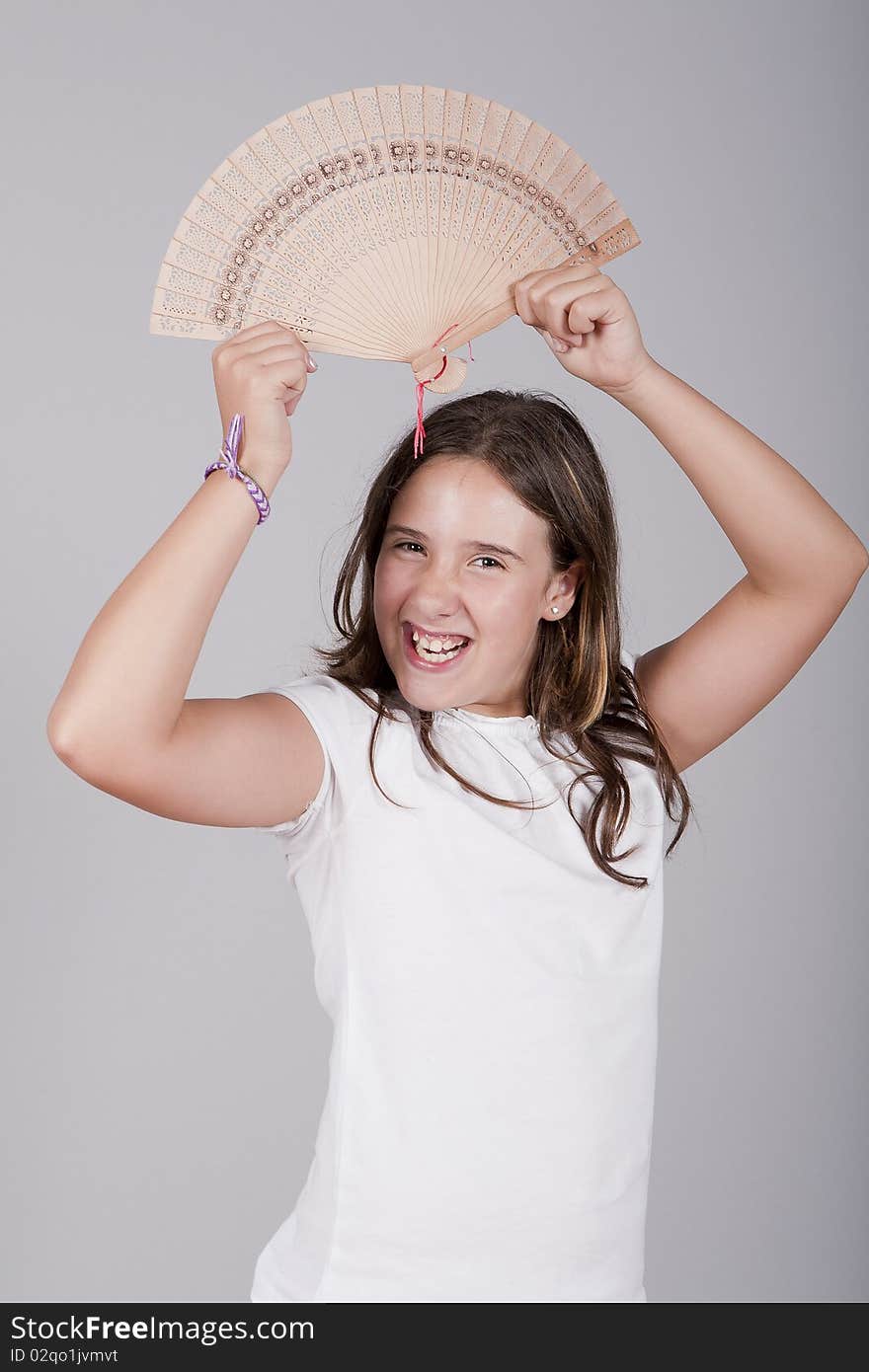 Young girl playing with a fan and smiling. Young girl playing with a fan and smiling