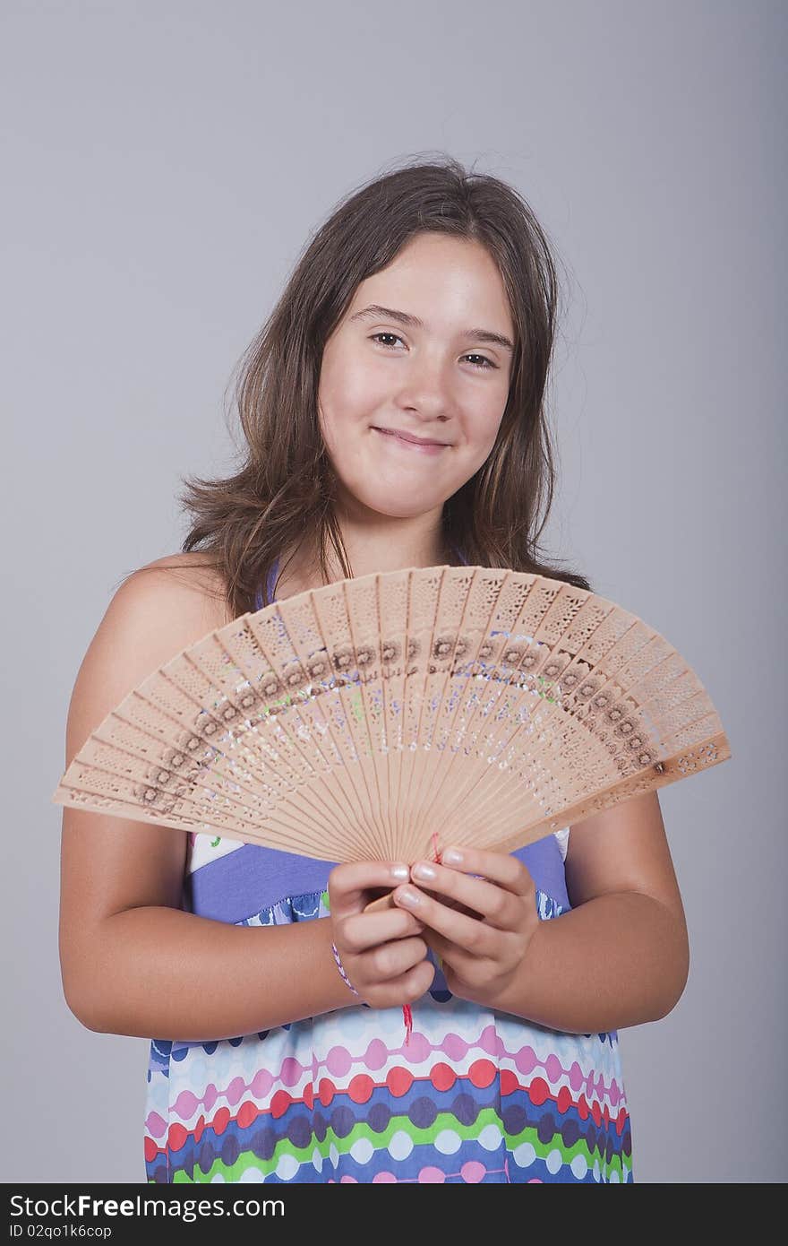 Young girl playing with a fan and smiling. Young girl playing with a fan and smiling