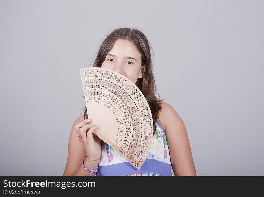 Young girl playing with a fan and smiling. Young girl playing with a fan and smiling