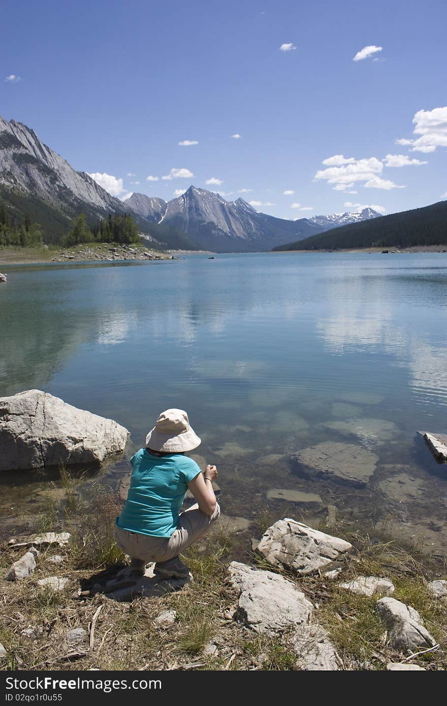 Woman sitting in front of a lake admiring the Canadian Rocky Mountains. Woman sitting in front of a lake admiring the Canadian Rocky Mountains