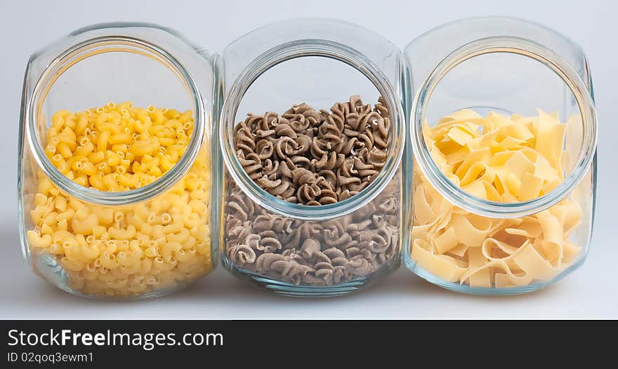 Pasta in glass jars on white background