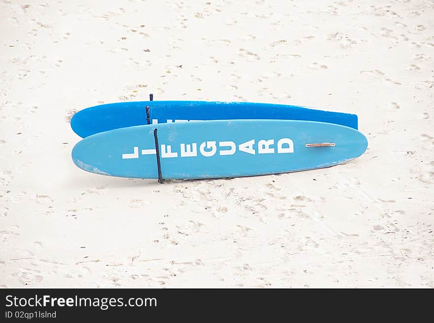 A pair of lifeguard surfboards on a white sand beach