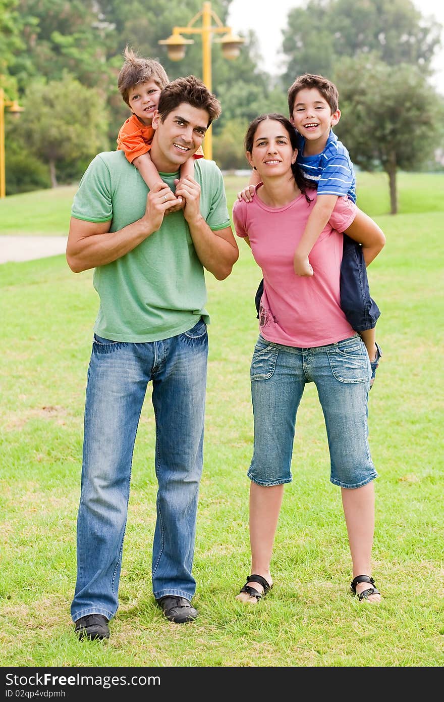 Couple giving piggyback ride to their children and looking into camera