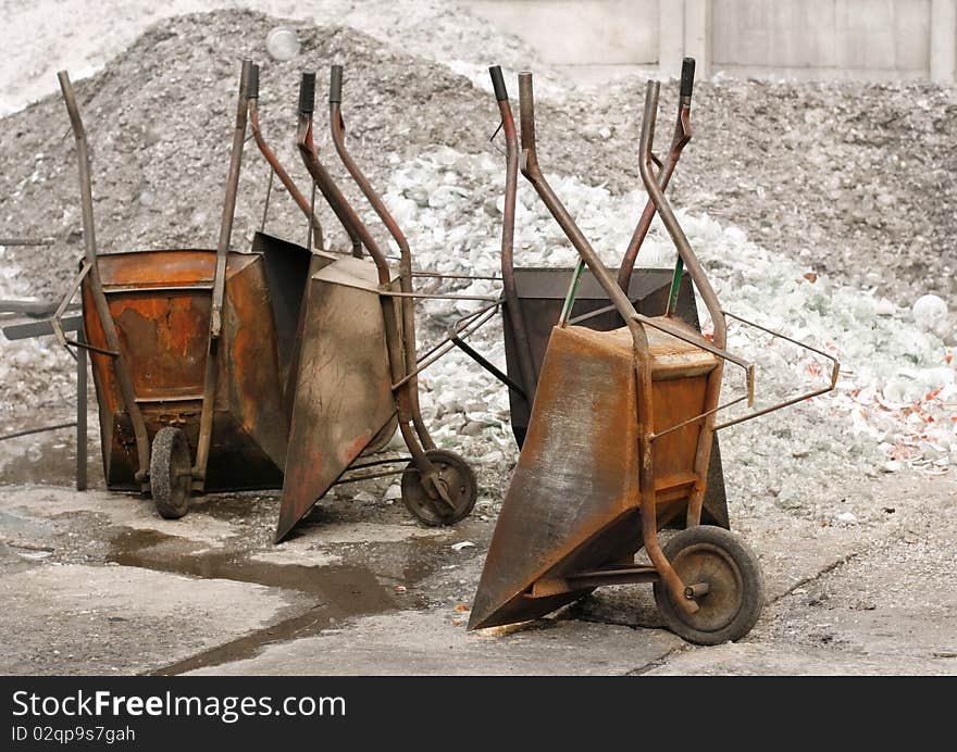 Empty, old wheelbarrows on the background of heaps of rubble, lack of hands to work. Empty, old wheelbarrows on the background of heaps of rubble, lack of hands to work