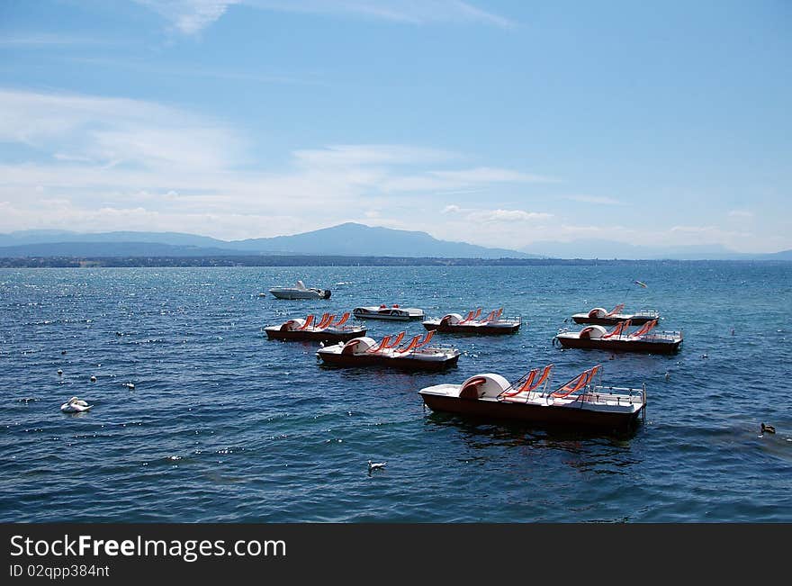 Pedal boats   waiting to be used with lake scene and mountains in the background. Pedal boats   waiting to be used with lake scene and mountains in the background.