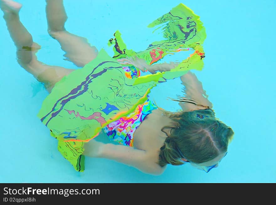 A young girl swimming through a hoop under water. A young girl swimming through a hoop under water.