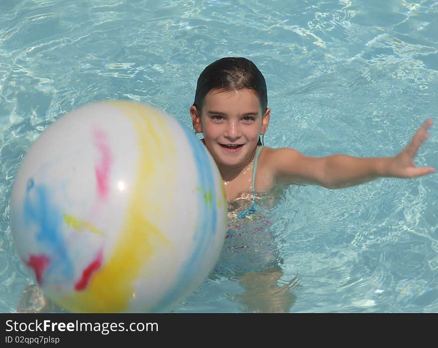 A young girl throwing a ball at the camera. She has ear plugs. A young girl throwing a ball at the camera. She has ear plugs.