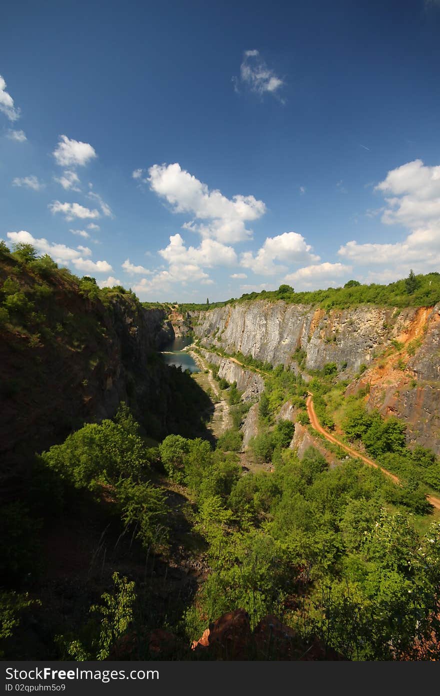 Deep desserted mine with the lake and blue cloudy skies. Deep desserted mine with the lake and blue cloudy skies