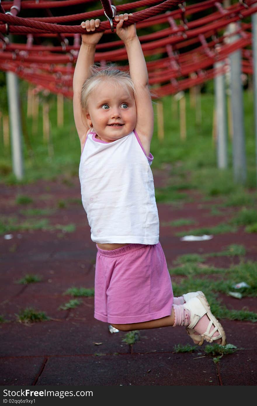 Cute little hanging from red ropes in the park. Cute little hanging from red ropes in the park