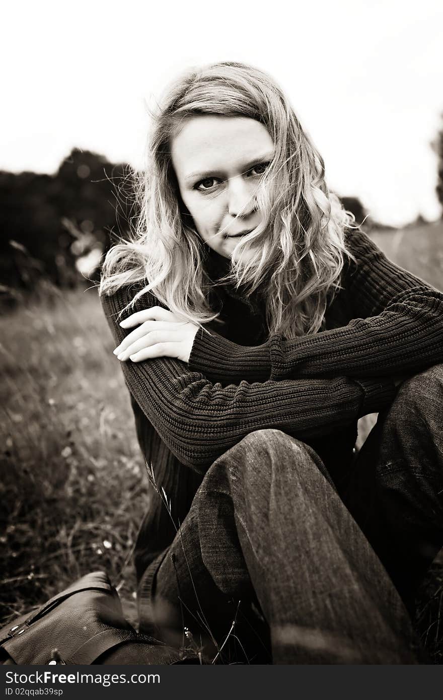 Portrait of pretty smiling girl sitting in the meadow, sepia toned. Portrait of pretty smiling girl sitting in the meadow, sepia toned.