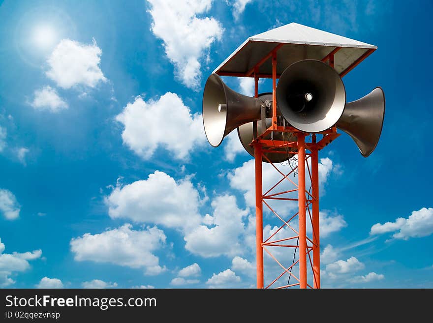 Lots of loudspeakers on a tall with blue sky