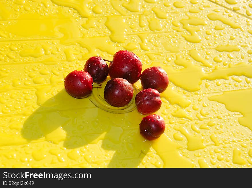 Group of fresh plum on plastic yellow table after rain