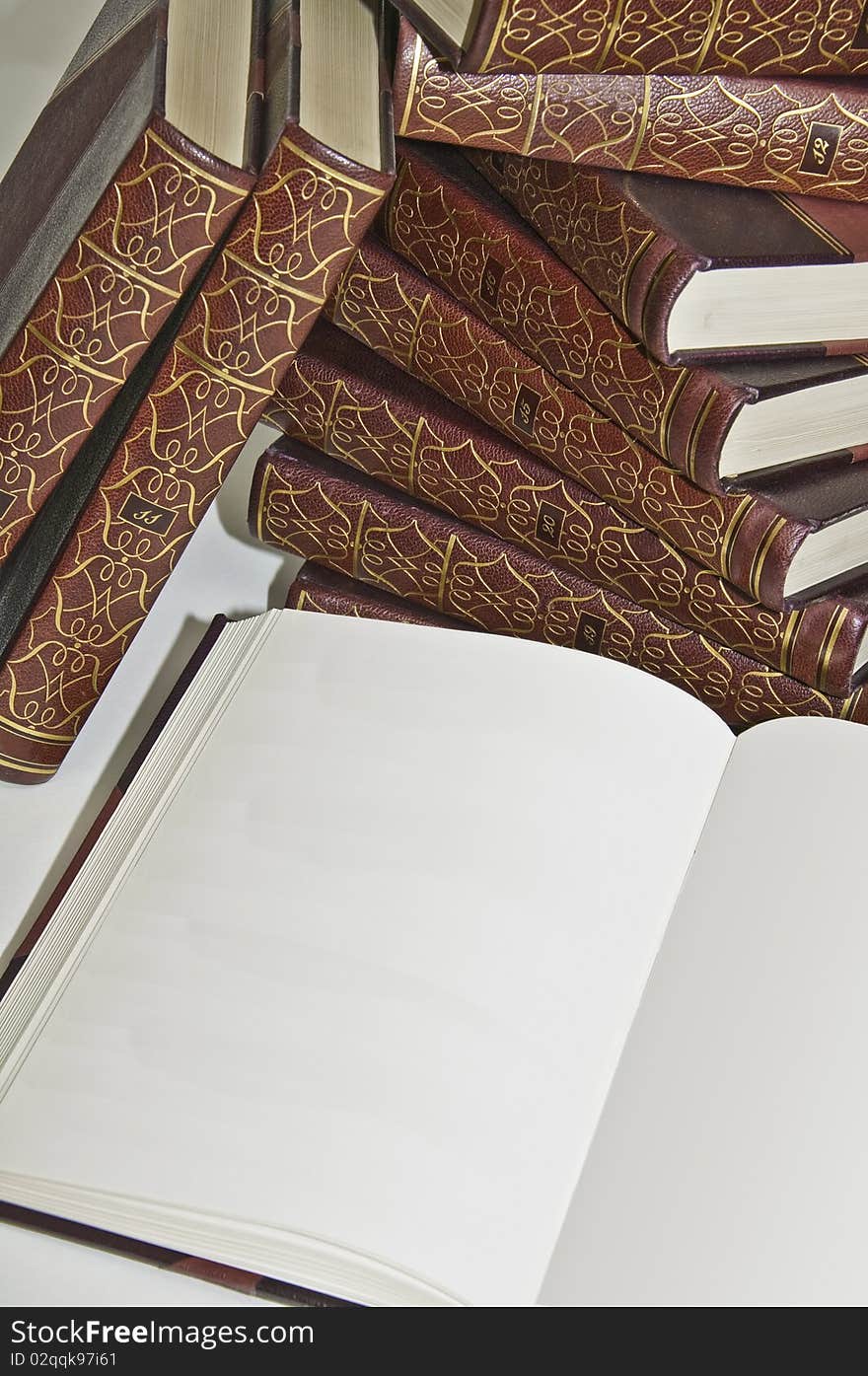 This image shows a collection of old books, stacked with open, showing a blank page. This image shows a collection of old books, stacked with open, showing a blank page