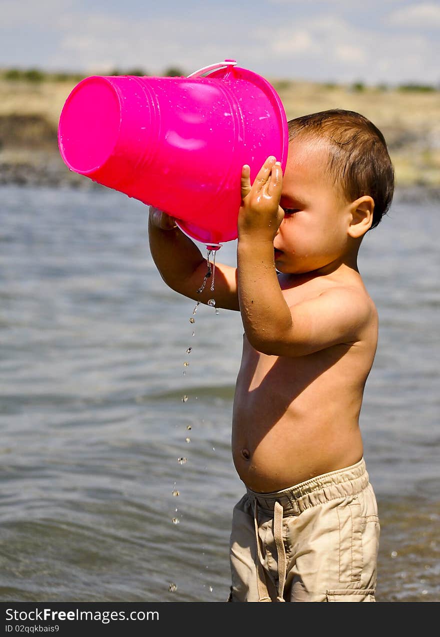 child plays with a bucket on the river. child plays with a bucket on the river