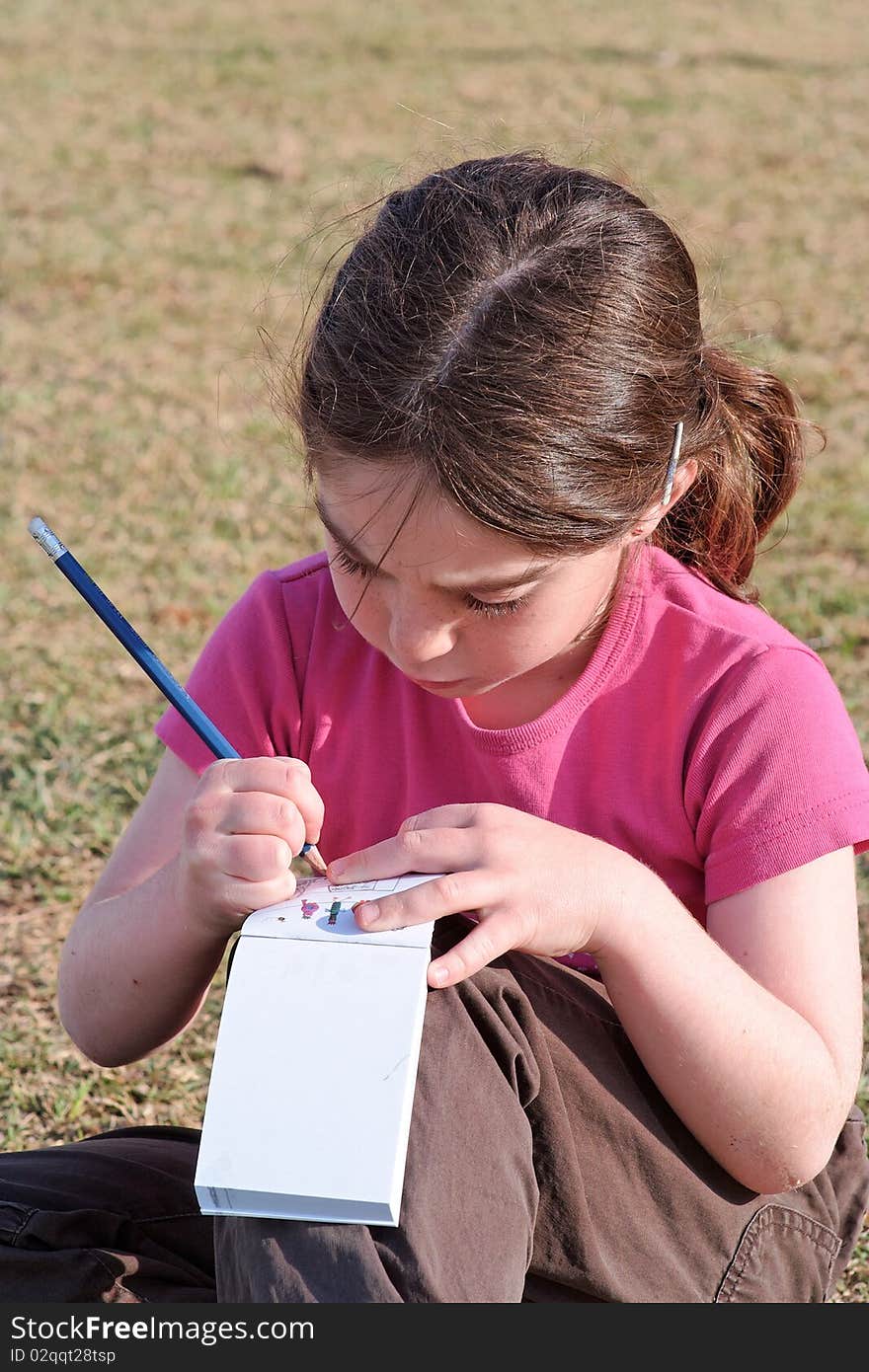 Cute little girl with pigtails writes outdoor