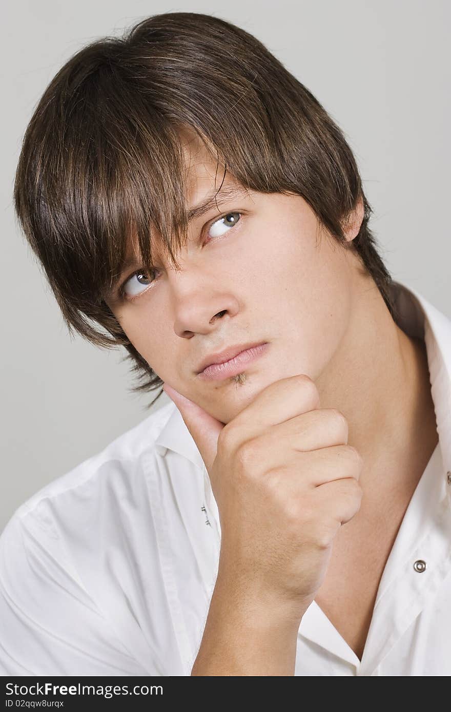 Closeup of a handsome young man thinking against white background