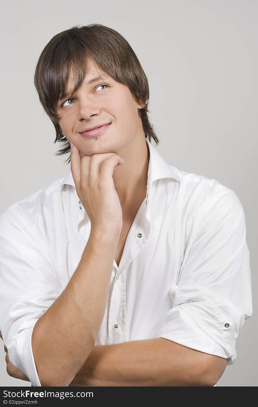 Closeup of a handsome young man thinking against white background