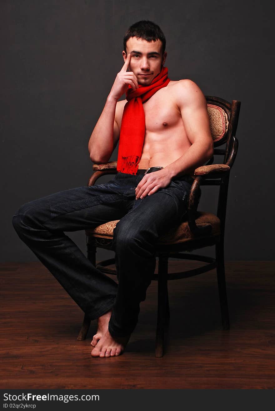 Young fashion man model with athletic body posing with a red scarf. Young fashion man model with athletic body posing with a red scarf