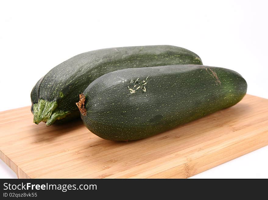 Two zucchinis on a chopping board on white background