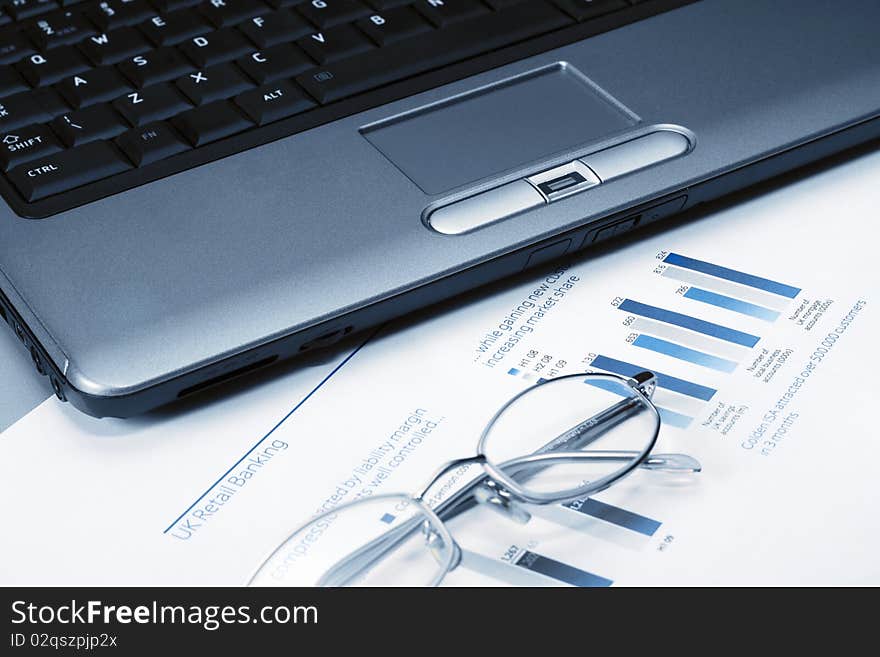 Picture of a glasses and laptop on a stock chart. Picture of a glasses and laptop on a stock chart.