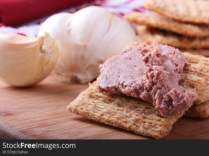 Wheat crackers on a kitchen board with meat paste.