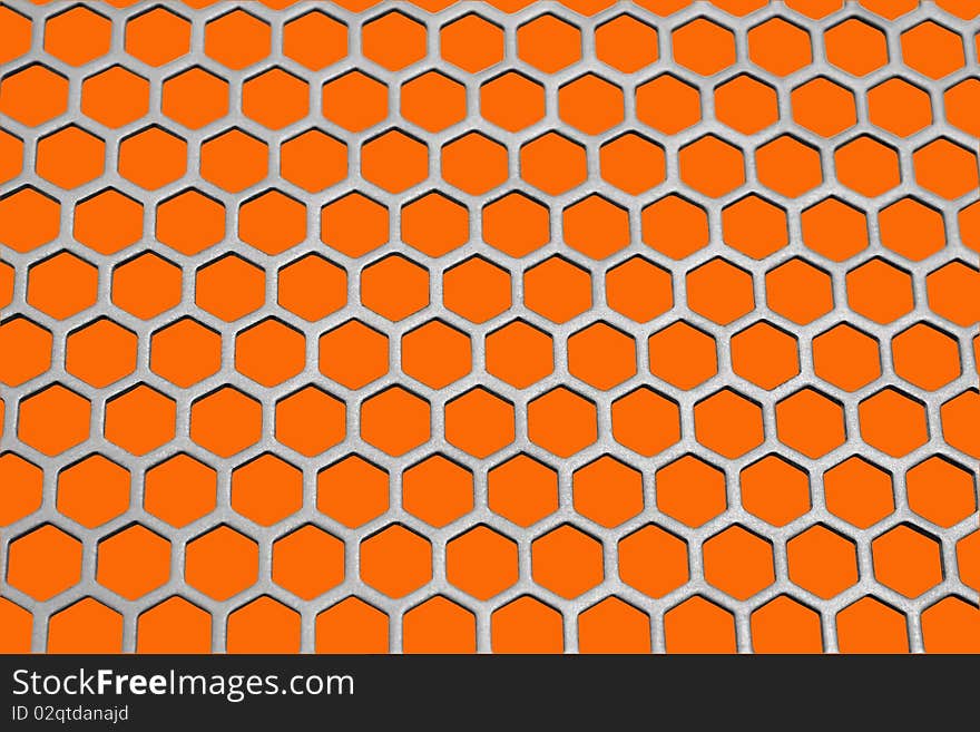 Aluminum honeycomb lattice in the form. Close-up. On an orange background. Aluminum honeycomb lattice in the form. Close-up. On an orange background.