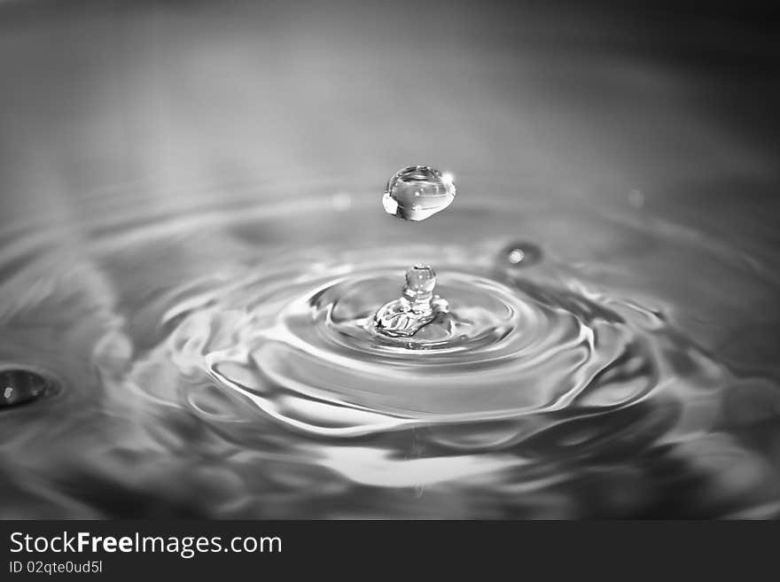 Clean blue drop of water splashing in clear water. Abstract blue background