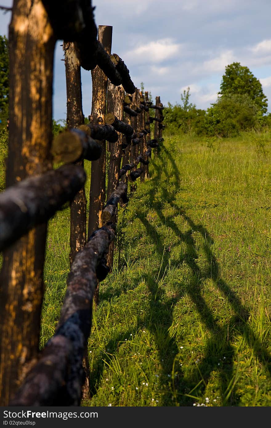 Meadow and wooden fence shadow