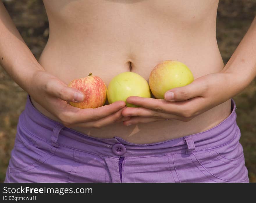 Girl holds the apples on a background of the stomach. Girl holds the apples on a background of the stomach