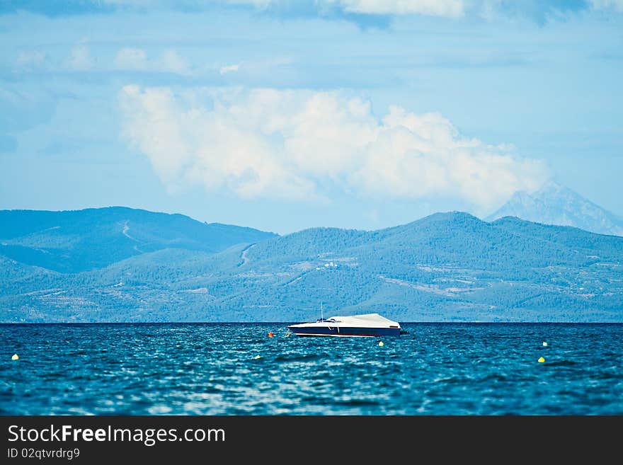 A beautiful white boat against the blue sky, sea and mountains in the background. Greece, Halkidiki, Kassandra. A beautiful white boat against the blue sky, sea and mountains in the background. Greece, Halkidiki, Kassandra.