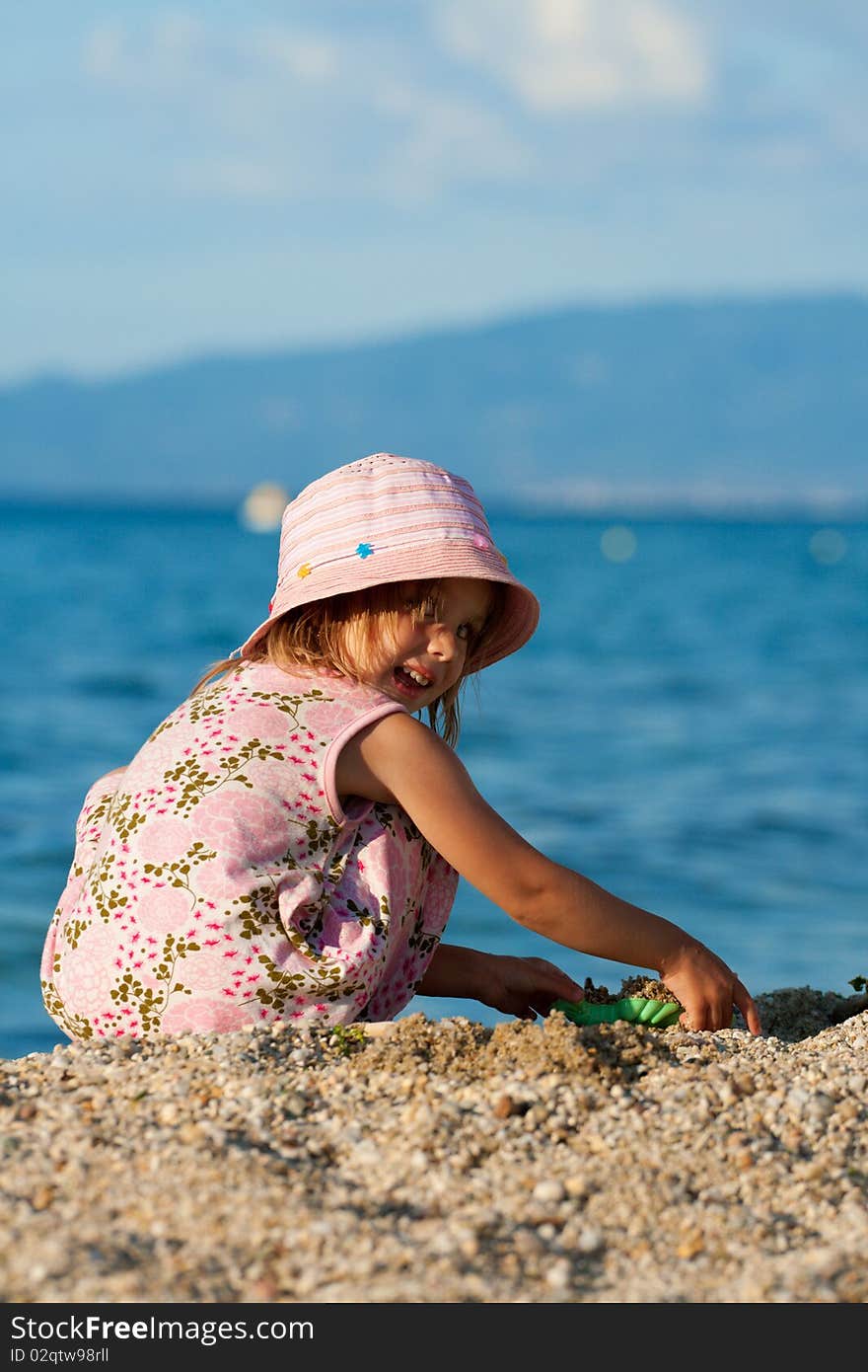 Beautiful little girl sitting and playing at the seacoast. Summer. Beautiful little girl sitting and playing at the seacoast. Summer.