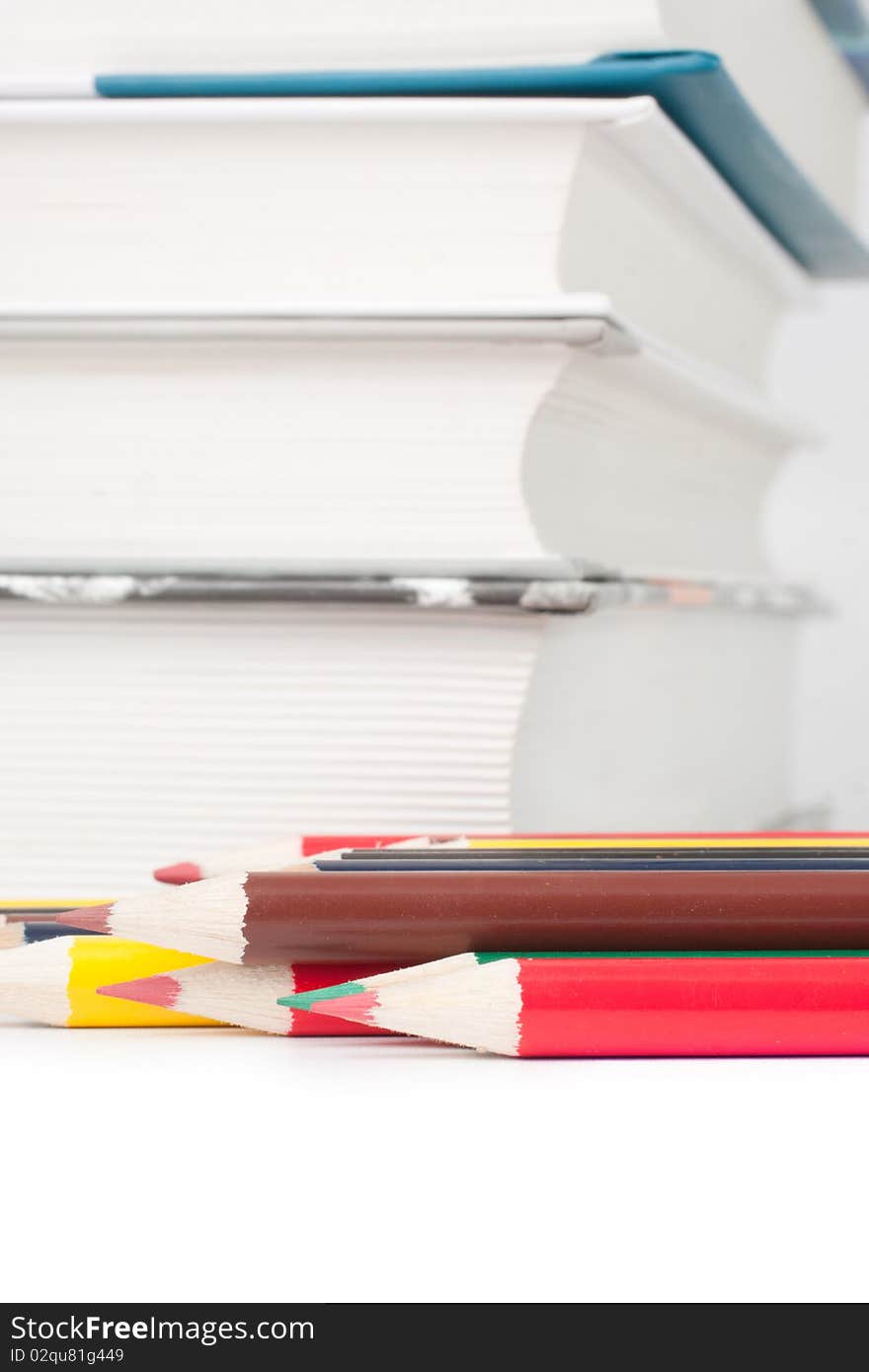 Books and colored pencils on a white background (selective focus)