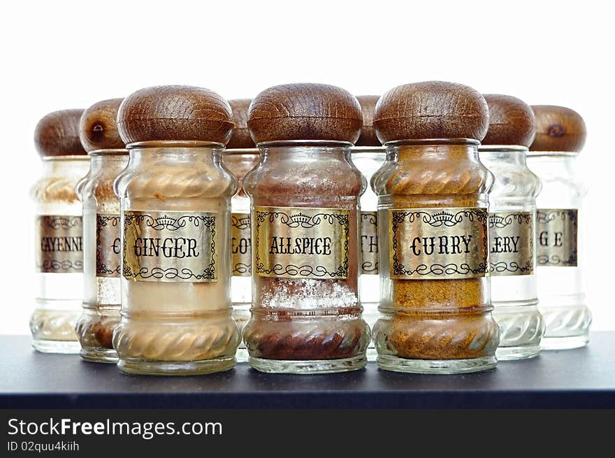 A variety of different spices on a black counter top.