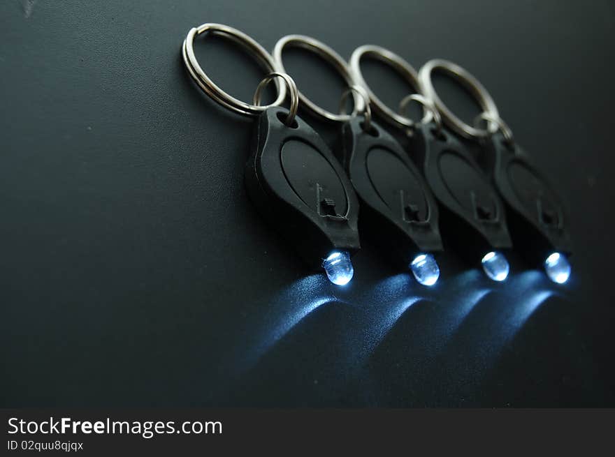 Miniature LED keychain lights on a black surface with shallow depth of field. Miniature LED keychain lights on a black surface with shallow depth of field.