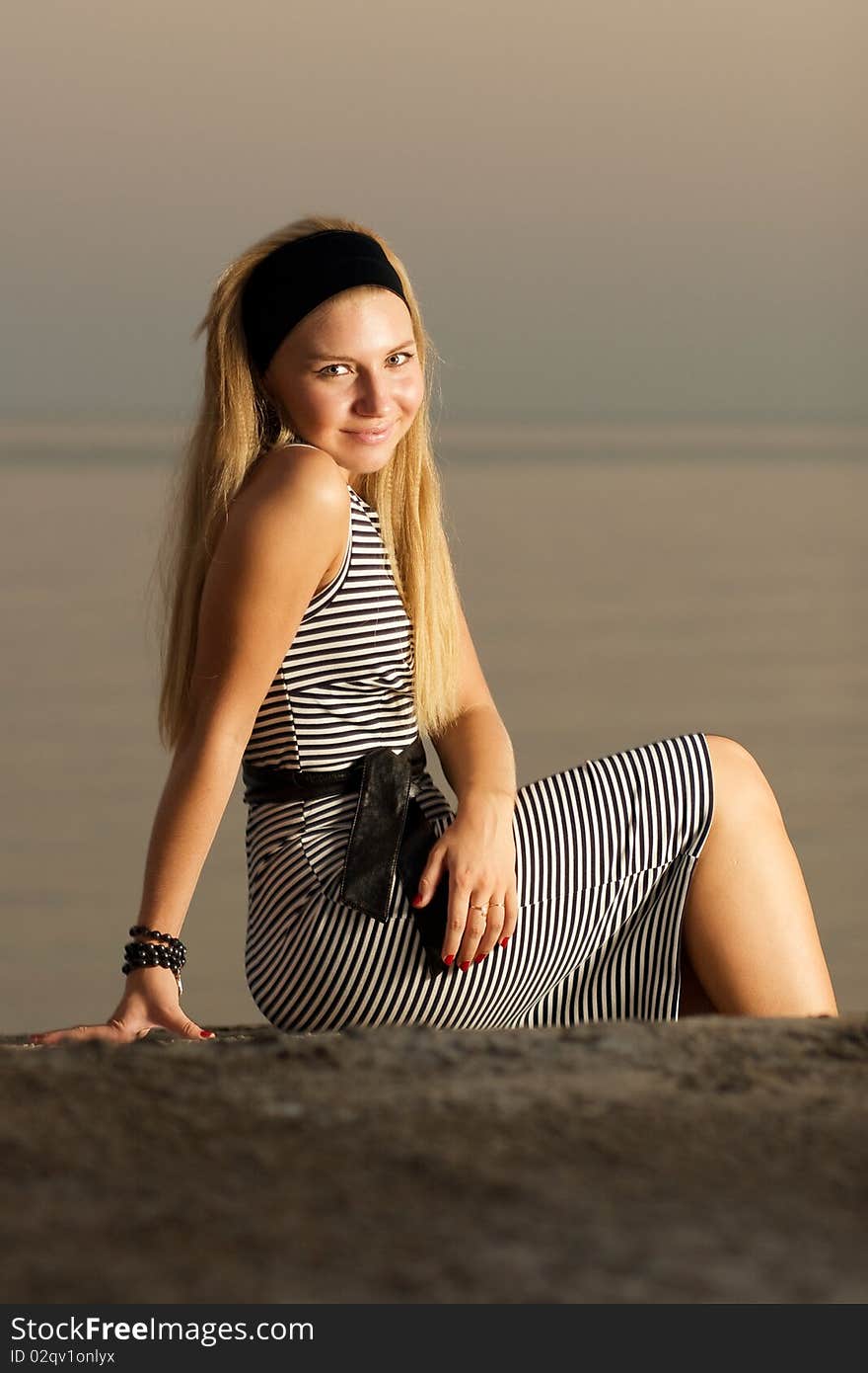 Girl Sitting In The Sunset At The Seaside