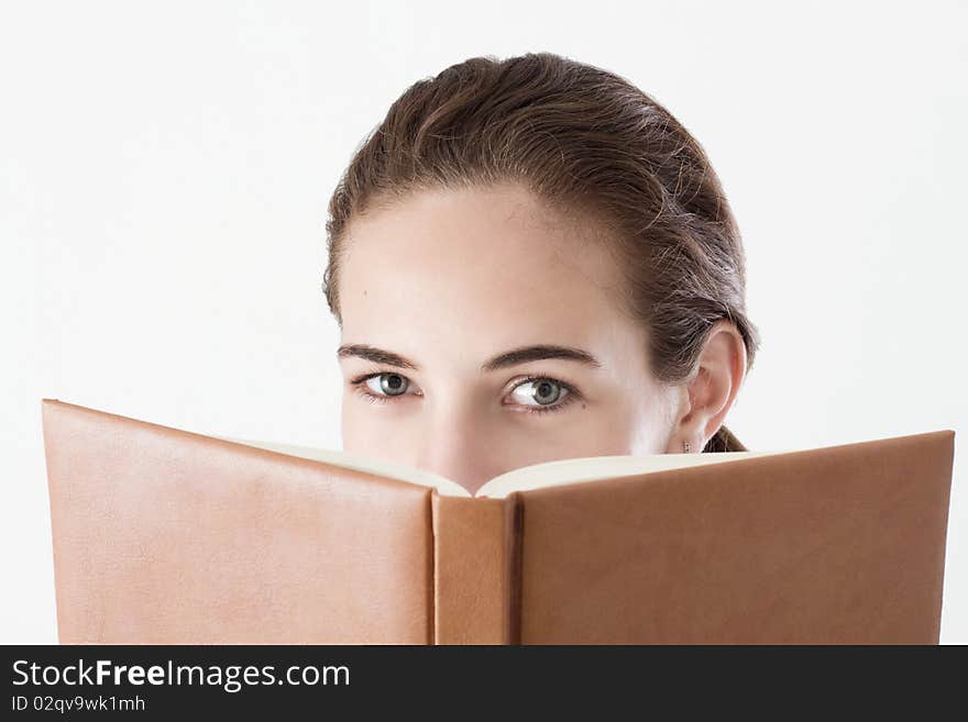 Teen girl reading, looking over the book. Studio shot.