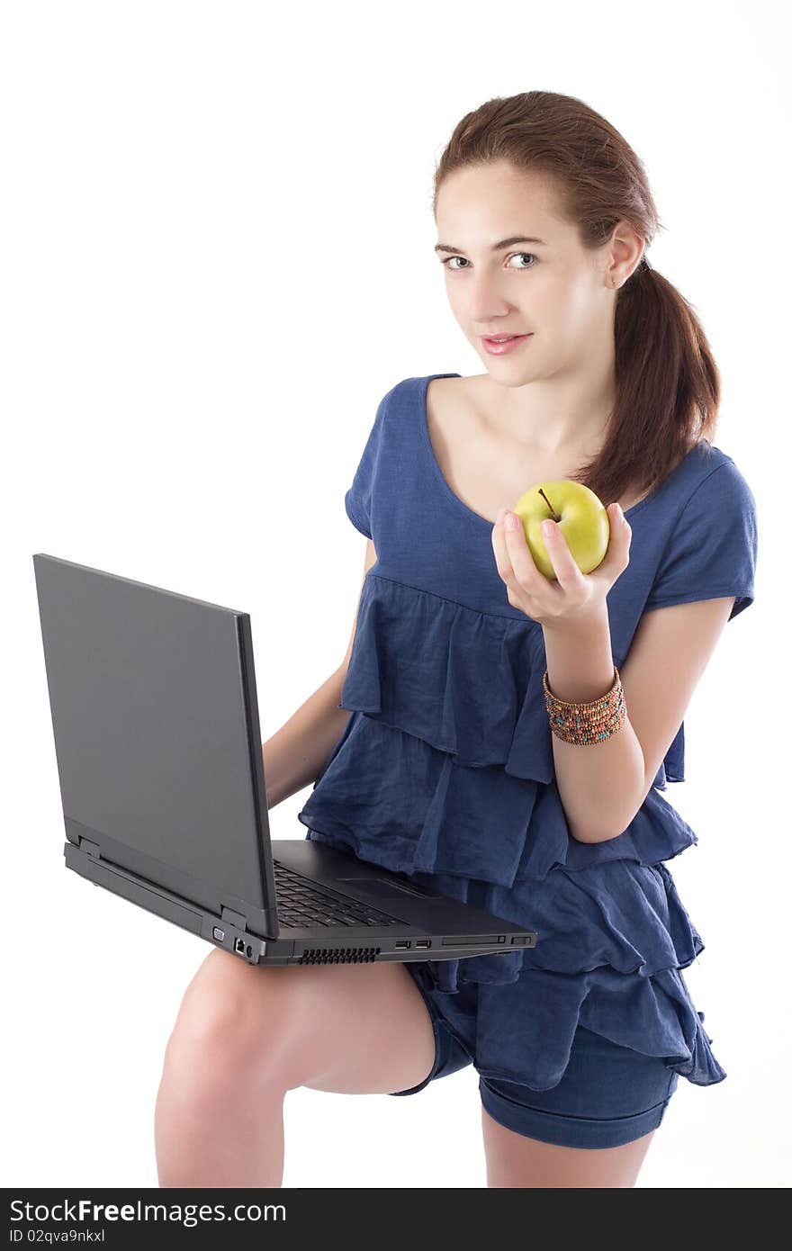 Teen girl, standing, holding laptop and a healthy snack, an apple. Studio shot. Teen girl, standing, holding laptop and a healthy snack, an apple. Studio shot.