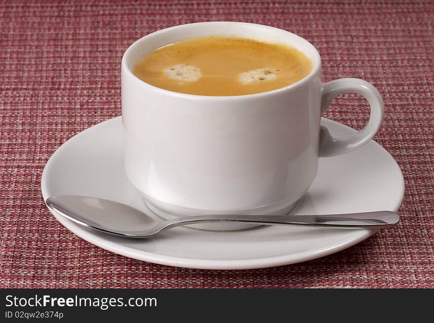 Little white espresso coffee cup on a white saucer over checked table-cloth background