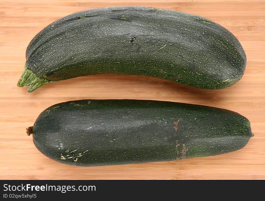 Two zucchinis on a chopping board on white background