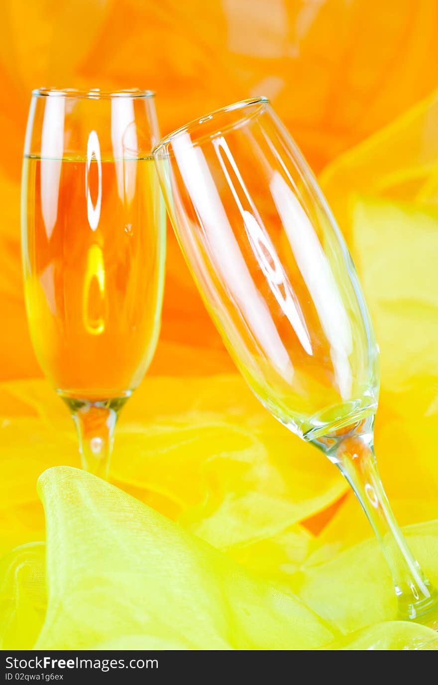 Two champagne glasses in front of orange background