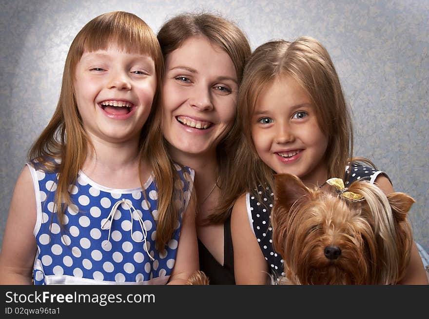 Young mother and two little sisters with Yorkshire terrier over light defocused background. Young mother and two little sisters with Yorkshire terrier over light defocused background