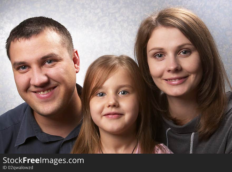 Young mother, father, and daughter over light defocused background. Young mother, father, and daughter over light defocused background