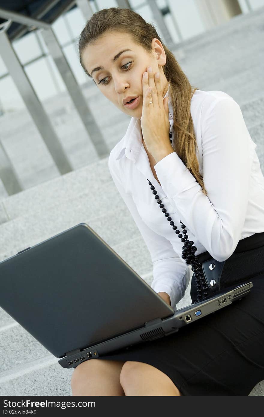 Business woman running on a laptop. He sits on the stairs office building. Business woman running on a laptop. He sits on the stairs office building