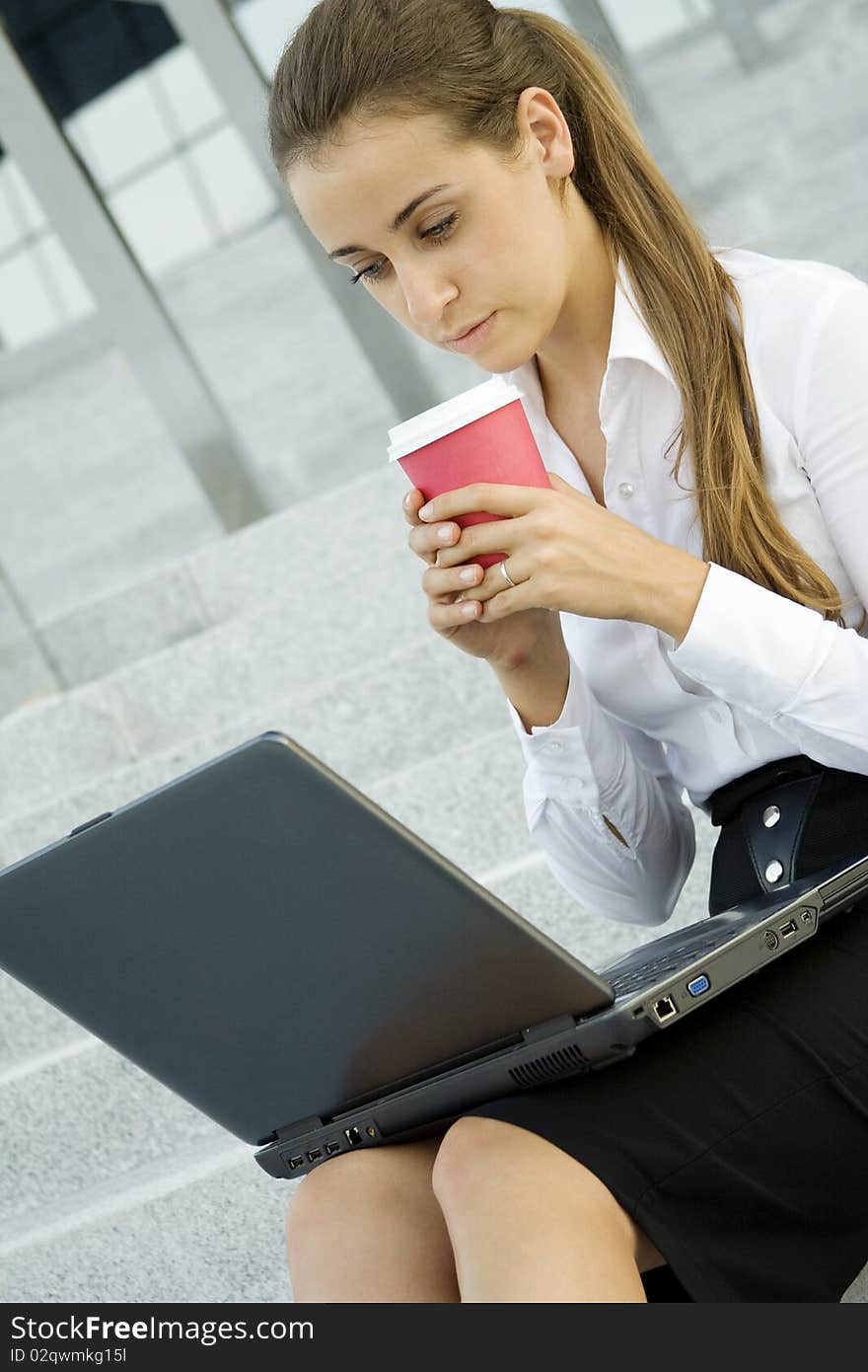 Young, beautiful woman business over coffee in the fresh air sitting on the stairs, office building, next to the laptop. Young, beautiful woman business over coffee in the fresh air sitting on the stairs, office building, next to the laptop.