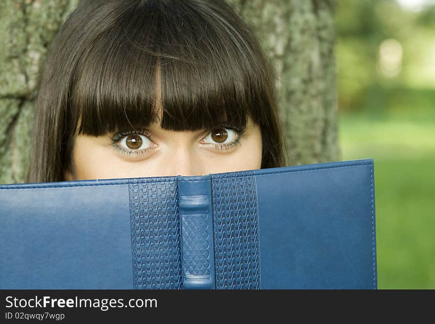 Young beautiful woman in a park with a notebook. Young beautiful woman in a park with a notebook