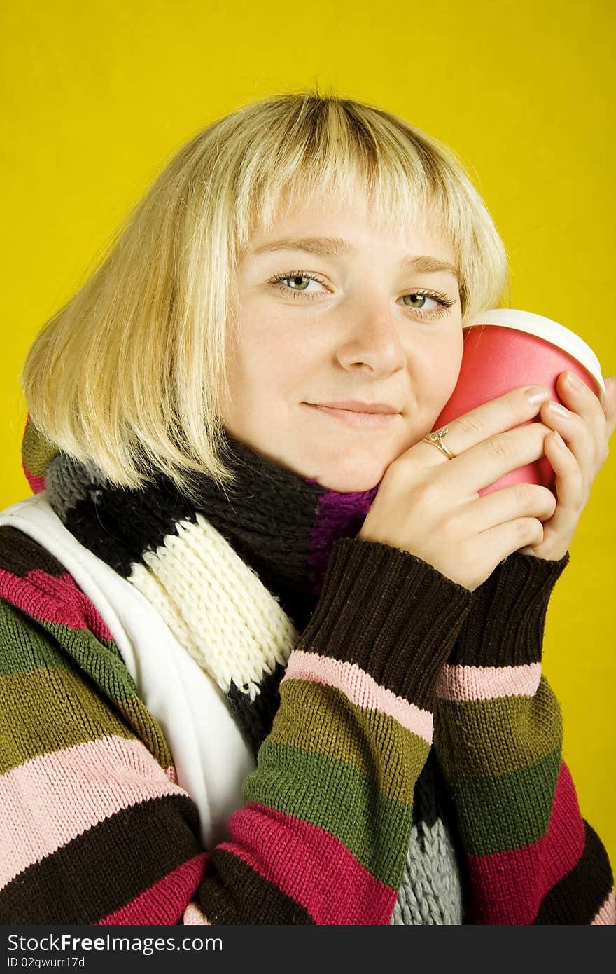 Young woman in sweater and scarf clasps to face a papercup of coffee. Winter. Young woman in sweater and scarf clasps to face a papercup of coffee. Winter