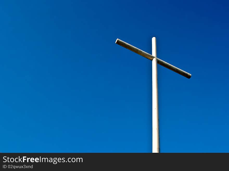 Under a deep blue sky stands a Cristian Cross made from welded pipe. Under a deep blue sky stands a Cristian Cross made from welded pipe.