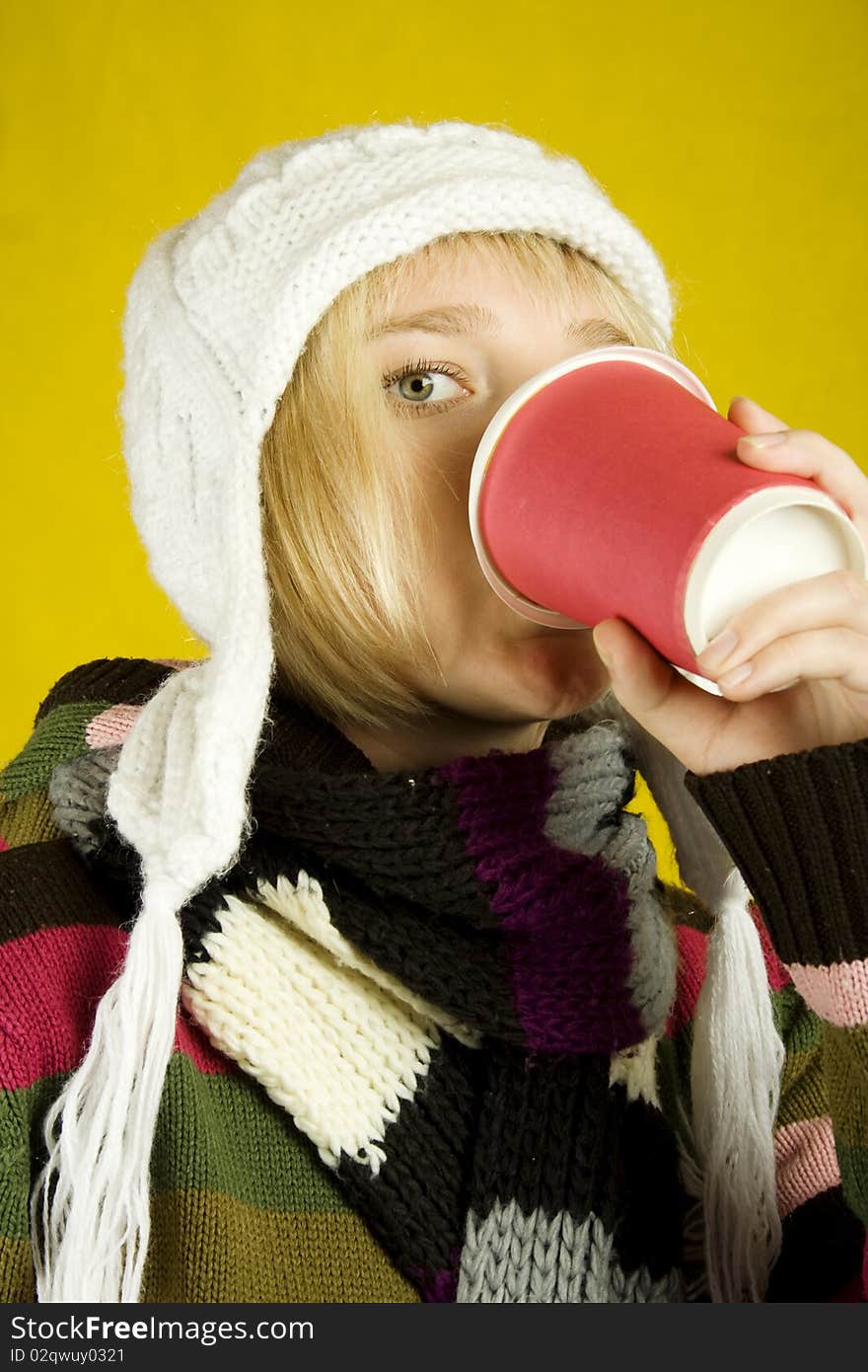 Young woman in a warm sweater, scarf and hat holding a paper cup of coffee. Winter. Young woman in a warm sweater, scarf and hat holding a paper cup of coffee. Winter