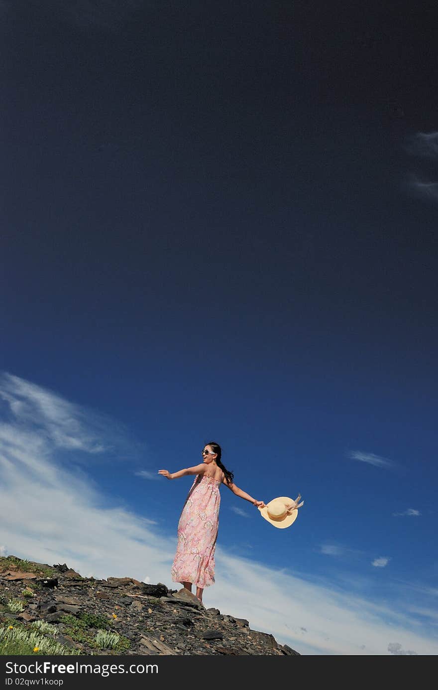 Girl is going round and round under the blue sky on the grassland.